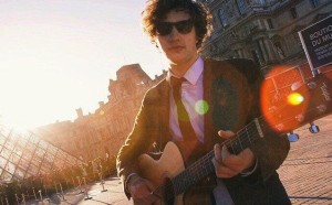 Image: Roar News / Phil playing the guitar outside Paris' Louvre